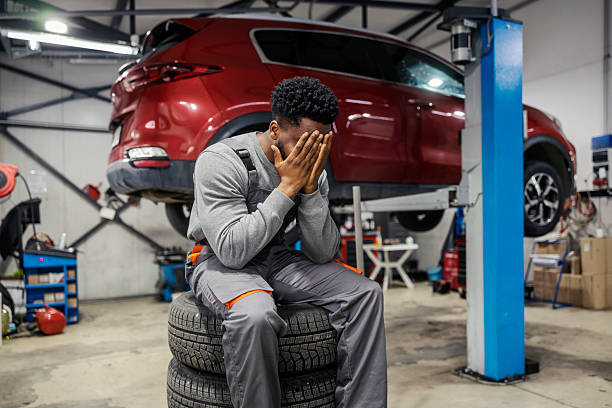 Mechanic sitting on tires looking stressed